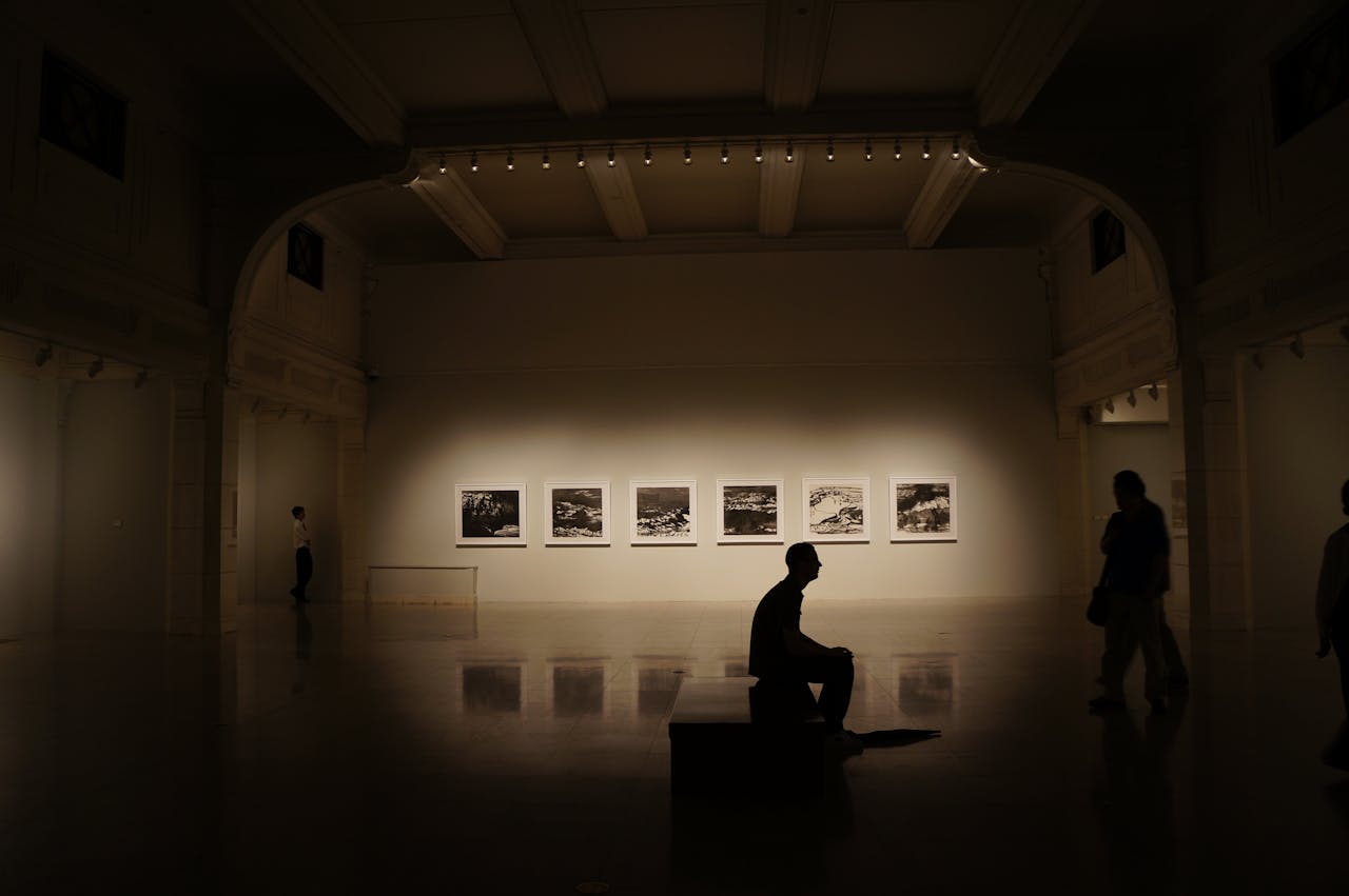 about-01 A dimly lit gallery showcasing silhouettes and framed photographs, creating a serene atmosphere.